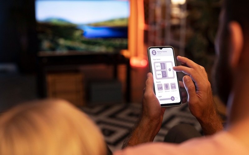 iPhone displaying a TV remote app while controlling a Smart TV in a living room